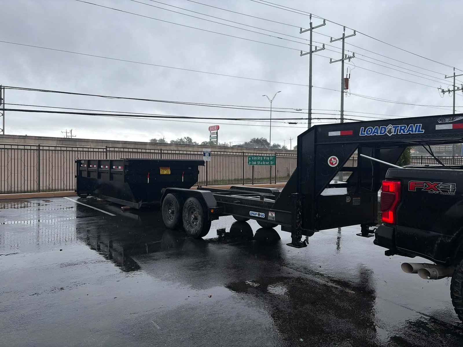 Roll-off dumpster set down from the trailer in a wet parking lot