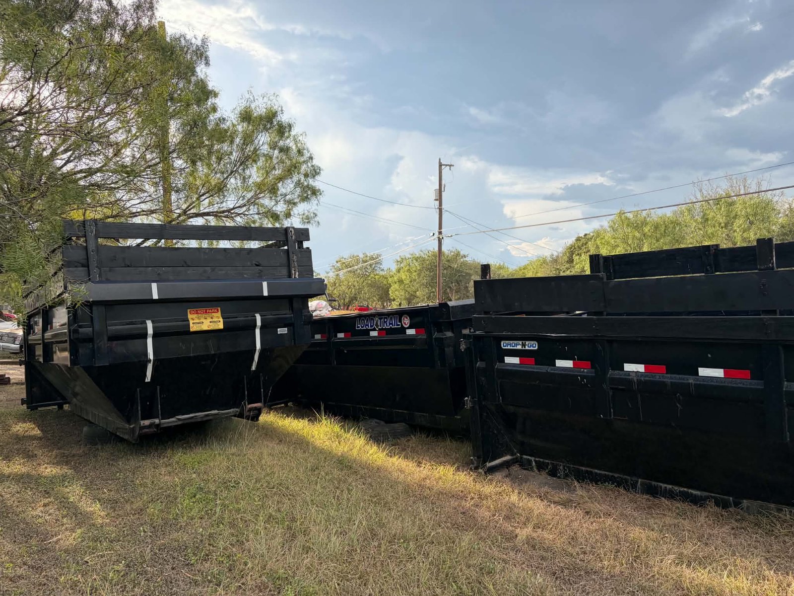 Three black roll-off dumpsters parked at the yard